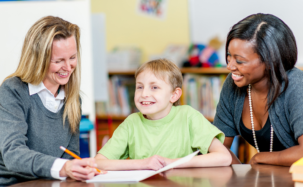 two women sitting with young boy in classroom